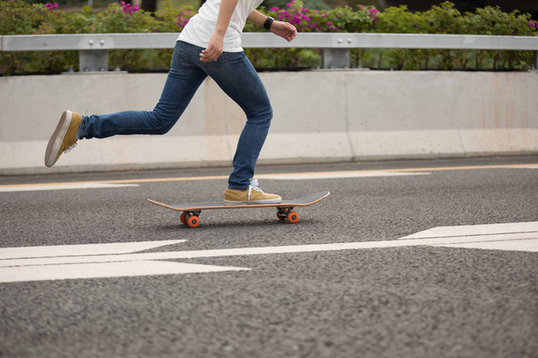 Cropped image of skateboarder sakteboarding on highway - 写真・画像
