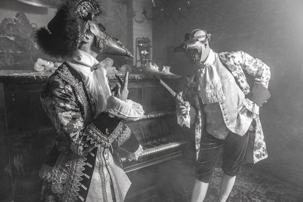 Actors in Steam punk masks and antique costumes indoor. Black-white photo. - Foto, afbeelding