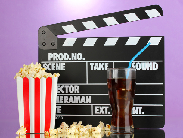Movie clapperboard, cola and popcorn on purple background - Photo, Image