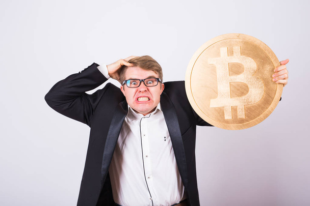 Portrait of a screaming businessman holds big golden bitcoin in his arms. Man in panic of cryptocurrency crash - Fotografie, Obrázek