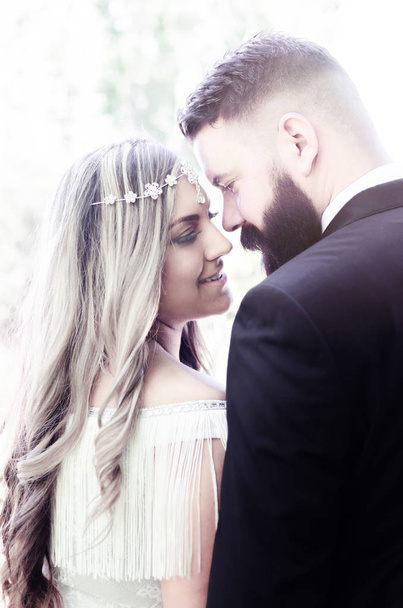 bride next to each other, love, Wedding couple outdoors is hugging each other. Beautiful model girl in white dress. Man in suit. Beauty bride with groom. Female and male portrait. Cute lady and handsome guy with long beard - Photo, Image