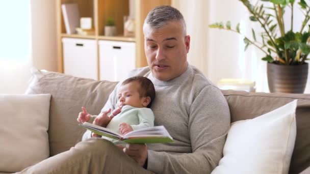 father reading book for little baby boy at home - Filmati, video