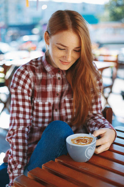 Girl with big cup of coffee at a wooden table outdoors - Fotoğraf, Görsel
