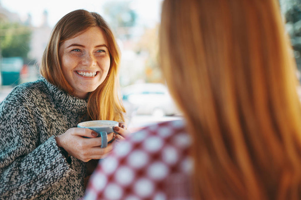 Усміхнені молоді жінки п'ють каву
  - Фото, зображення