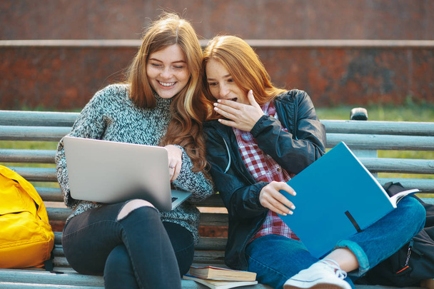 Estudiantes universitarios mirando a la pantalla del ordenador portátil sonriendo sorprendidos
 - Foto, Imagen