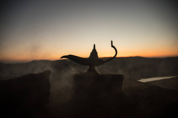 Antique rzemieślniczy Aladdin Arabian nights genie styl Lampa naftowa z miękkiego światła białego dymu. Zachód słońca na tle. Lampa z życzeniami - Zdjęcie, obraz