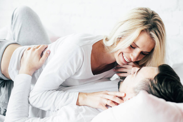 Jeune couple relaxant, embrasser et s'amuser couché sur le lit
. - Photo, image