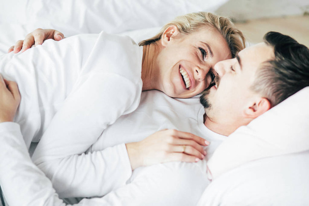 Young couple relaxing, embrace and have fun lying on the bed. - 写真・画像