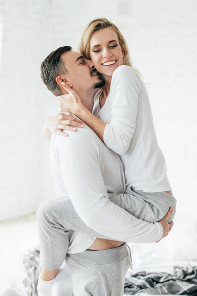 Hombre sosteniendo a su esposa en sus brazos y besándola. De interior
 - Foto, imagen