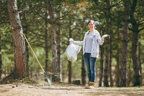 Молодая улыбающаяся женщина убирает мусор с мешками для мусора и спреем
 - Фото, изображение