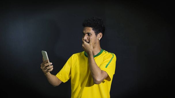 Férfi sportolók, vagy sárga egységes látszó mobiltelefon blac ventilátor - Fotó, kép
