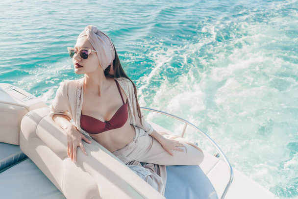 a luxurious rich woman in sunglasses enjoys a sea voyage on a white yacht - Фото, зображення