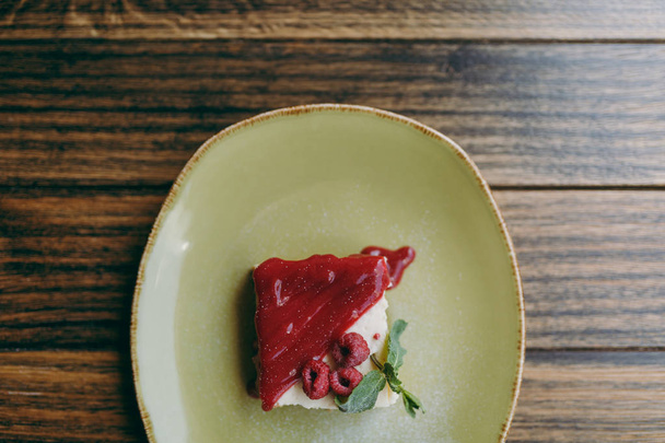 Закрыть десертный чизкейк с малиновым соусом на тарелке
 - Фото, изображение