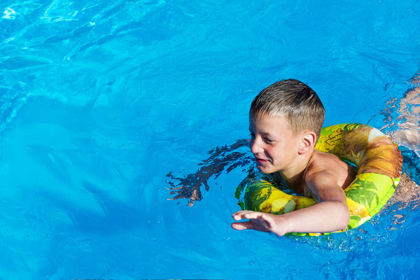 Kid having fun in the swimming pool on inflatable ring. Summer vacation fun. - Photo, Image