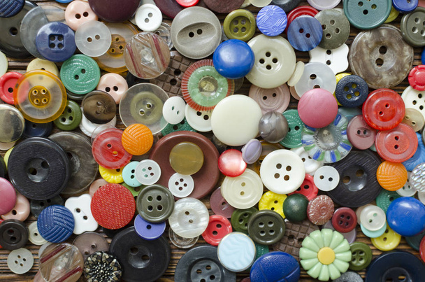 Colored plastic buttons on brown wooden background - Fotoğraf, Görsel
