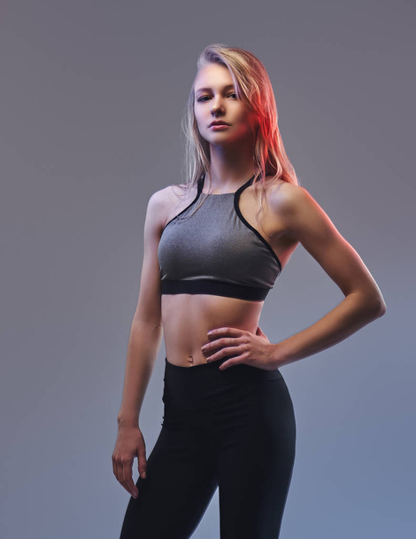 Sexy slim blonde girl in a sportswear posing in a studio. - Фото, изображение