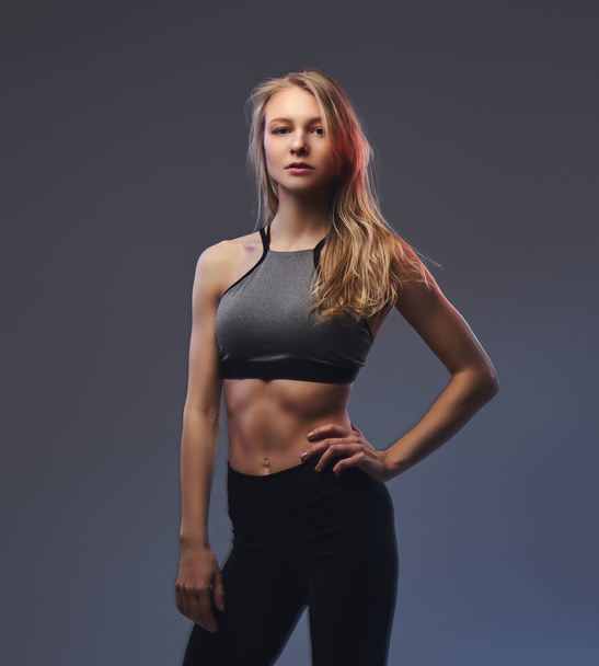 Sexy slim blonde girl in a sportswear posing in a studio. - Foto, imagen