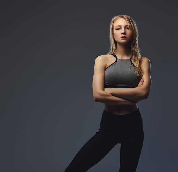Sexy slim blonde girl in a sportswear posing in a studio. - Photo, Image