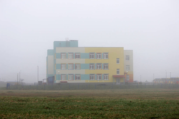 una casa solitaria colorata nella nebbia in un terreno vuoto in primavera presto al mattino
. - Foto, immagini