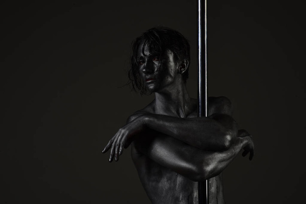 Man with nude torso covered with silver paint, black background. - Φωτογραφία, εικόνα