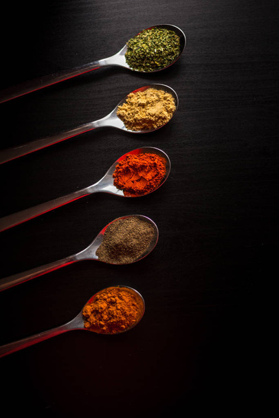 Spices colored in silver spoons - Foto, Bild