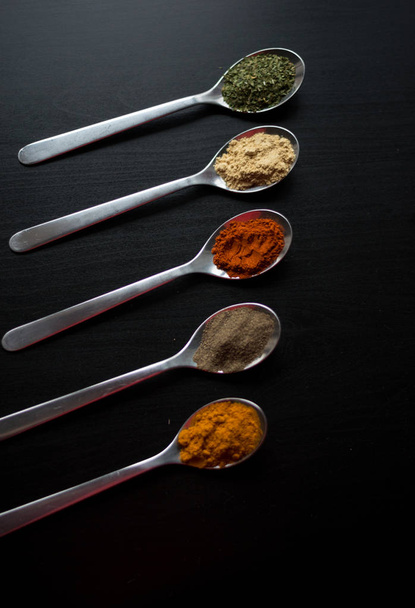 Spices colored in silver spoons - 写真・画像