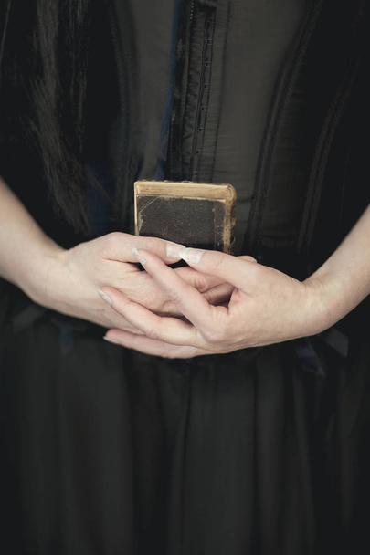 woman hands holding vintage old book, very dark atmospheric sensual rural, gothic studio shot can be used as background - Фото, изображение