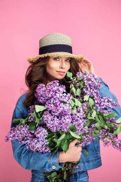 Щаслива усміхнена жінка насолоджується запахом бузкових квітів на барвистому синьому фоні
 - Фото, зображення