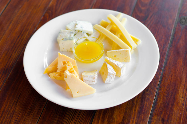 Cheese plate. Assortment of various types of cheese on wooden cutting board. - 写真・画像