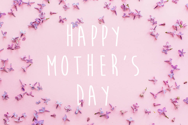 happy mother's day text, greeting card. beautiful lilac purple petals flowers on pink background - Photo, Image