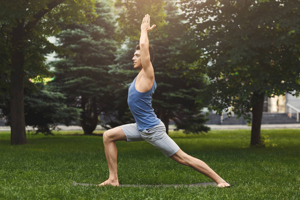 Young man practicing yoga outdoors - Foto, imagen