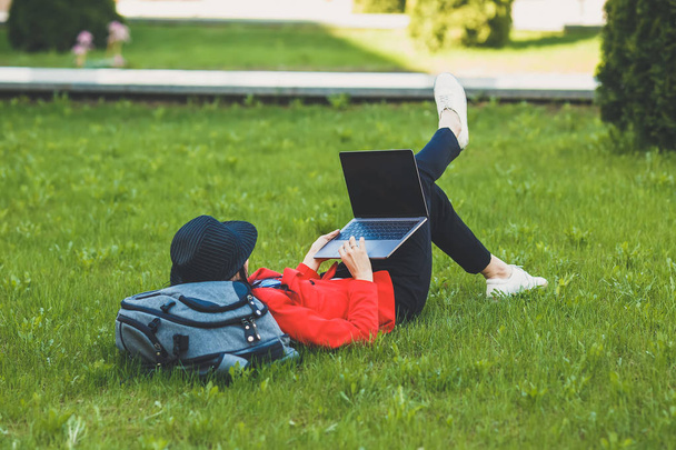 Happy bokovky mladá žena pracuje na notebooku pod širým nebem. Studentka pomocí přenosného počítače v areálu univerzity. Tónovaný obrázek. - Fotografie, Obrázek