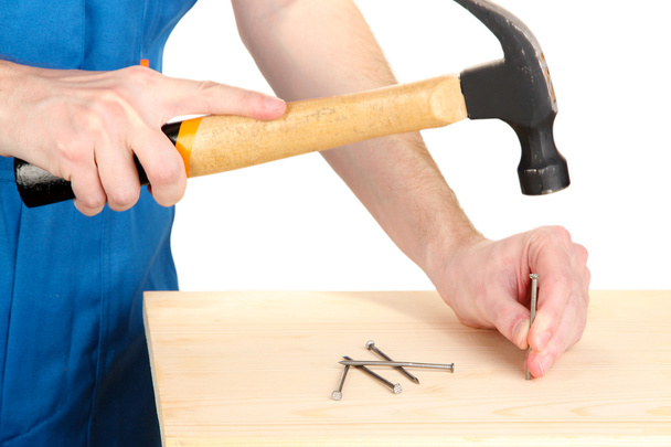 Builder hammering nails into board isolated on white - Φωτογραφία, εικόνα