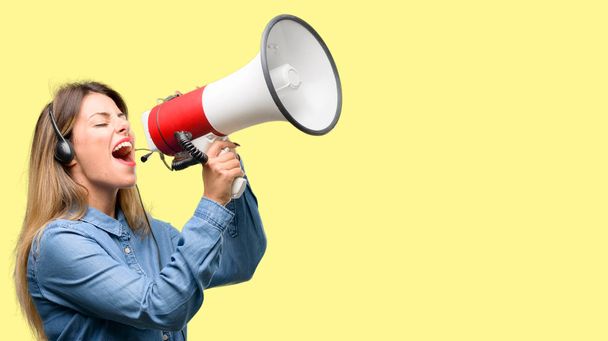Консультант колл-центра женщина в наушниках общается громко крича держа мегафон, выражая успех и положительную концепцию, идею для маркетинга или продаж
 - Фото, изображение