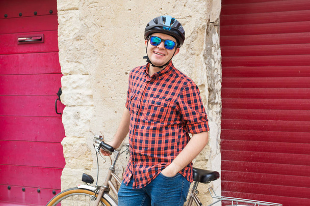 Handsome man hold bicycle on the backgound red outdoor - Photo, image