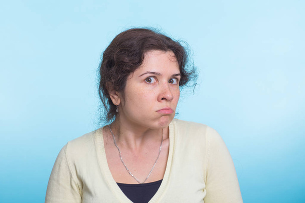 Porträt einer jungen wütenden Frau auf blauem Hintergrund - Foto, Bild