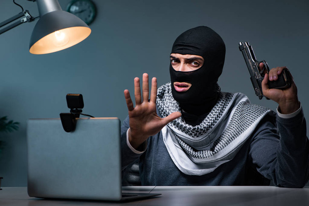 Terroristische inbreker met pistool werkend op computer - Foto, afbeelding
