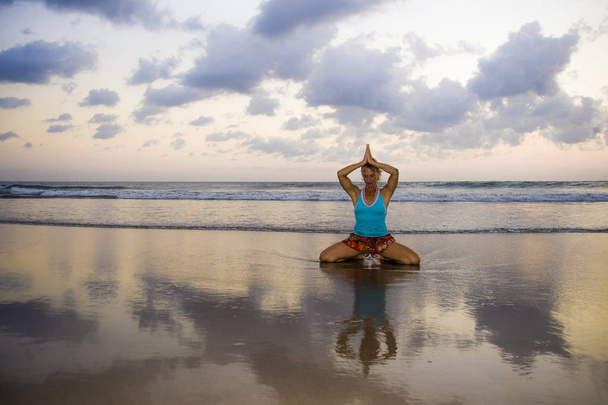 giovane donna in forma e attraente sport in spiaggia tramonto yoga pratica allenamento seduto sul sole bagnato di fronte al mare in meditazione e rilassamento esercizio
 - Foto, immagini