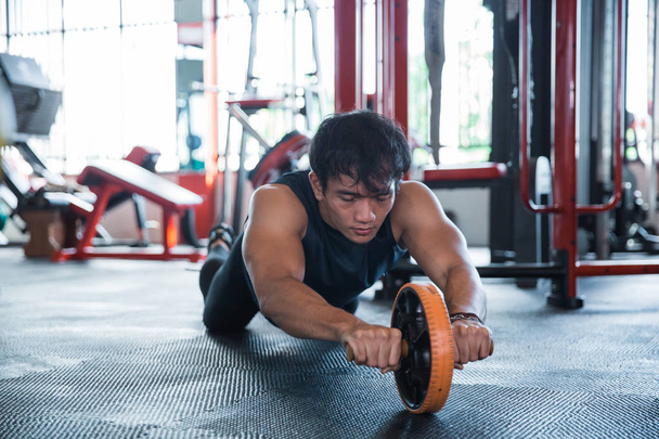 Front view man using abdominal roller  - Photo, image
