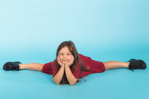 Beautiful girl sits on a splits. isolated on a blue background - Foto, imagen