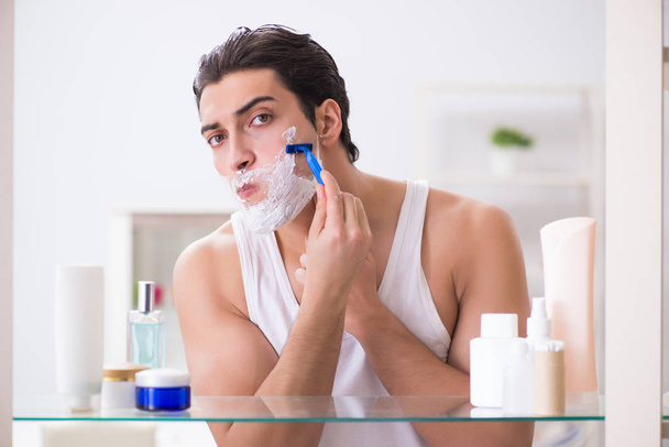 Young handsome man shaving early in the morning at home - Photo, Image