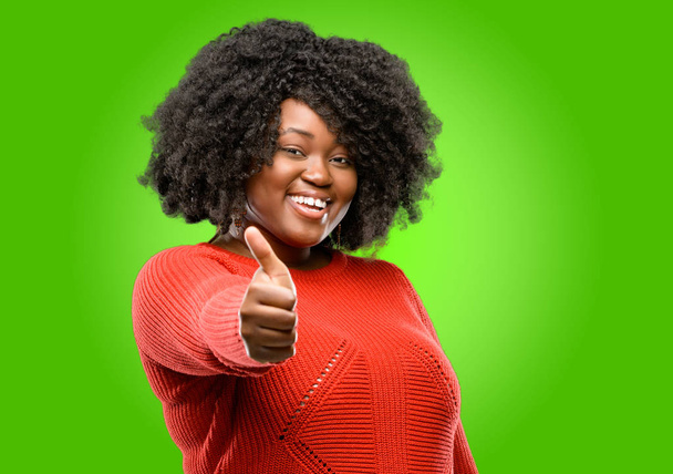 schöne afrikanische Frau lächelt breit und zeigt Daumen hoch Geste in die Kamera, Ausdruck von Sympathie und Zustimmung - Foto, Bild