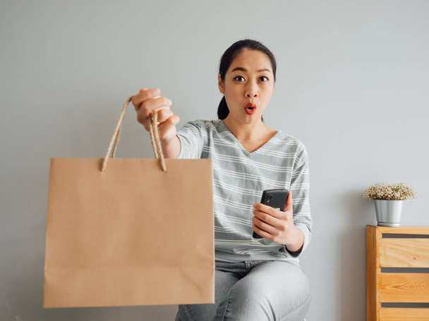 Woman showing off empty paper bag of product she purchased onlin - Foto, Imagen