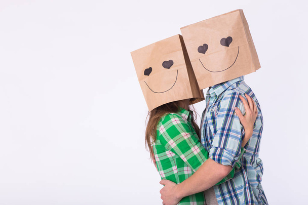 Love couple covering their faces with paper bag over white background with copyspace - Photo, Image