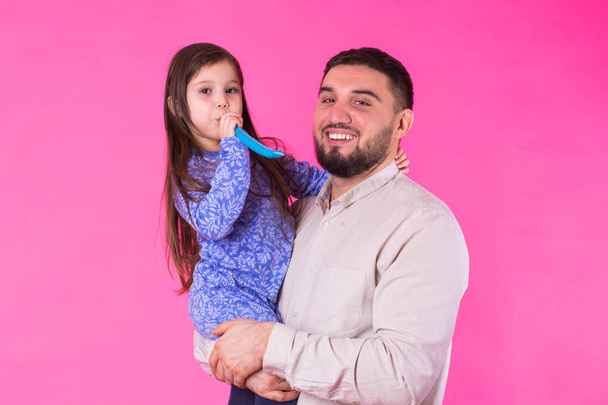 Happy father with his baby daughter on pink background - Foto, Imagen