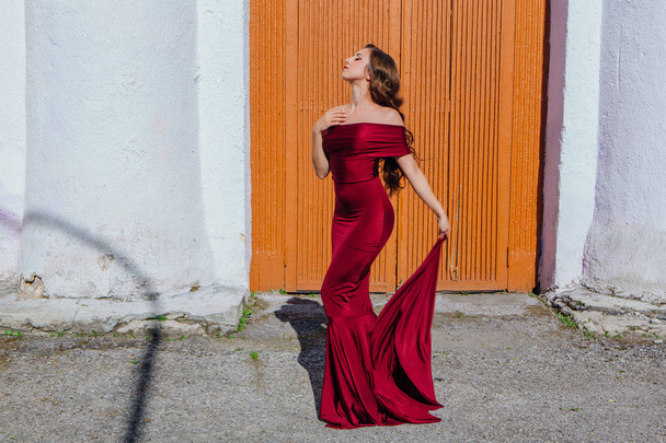 Beautiful young woman in a long red evening gown with a train - Fotoğraf, Görsel