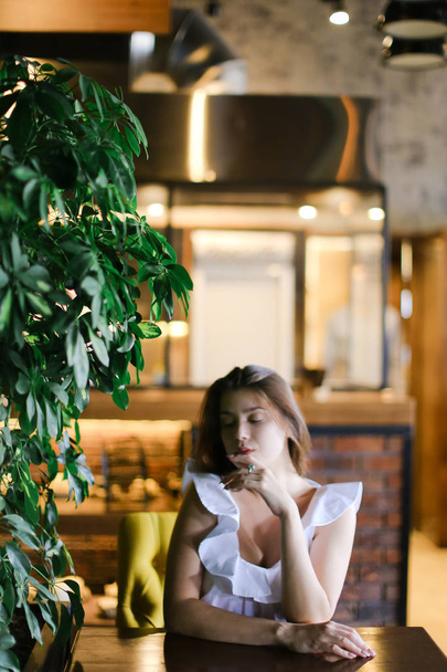 Piękna dziewczyna kaukaski odpoczynku w kawiarni i na sobie białą bluzkę z srebrny pierścień. - Zdjęcie, obraz