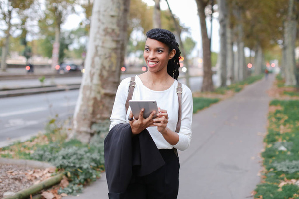 Siyah mutlu kız öğrenci ile tablet sokak ağaçları ile yakın yürüme. - Fotoğraf, Görsel
