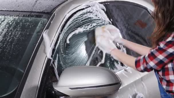 Młoda kobieta, mycia samochodu z gąbką - Materiał filmowy, wideo
