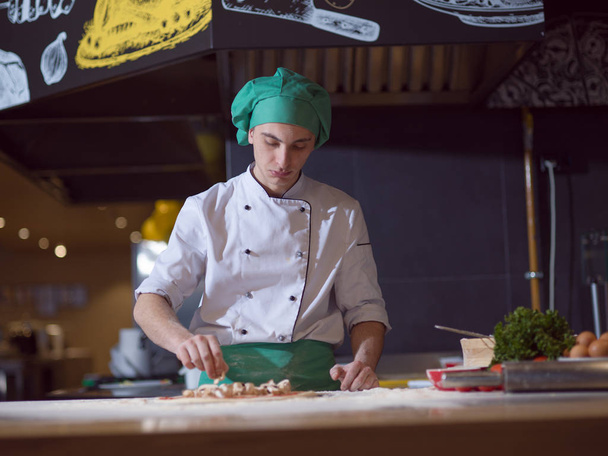 chef putting fresh mushrooms over pizza dough on kitchen table - Φωτογραφία, εικόνα
